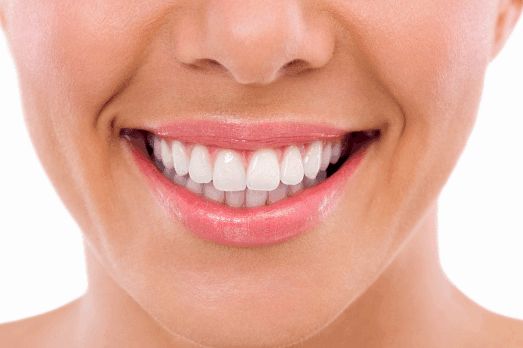 A close-up of a person smiling, showing perfect white teeth and healthy gums.