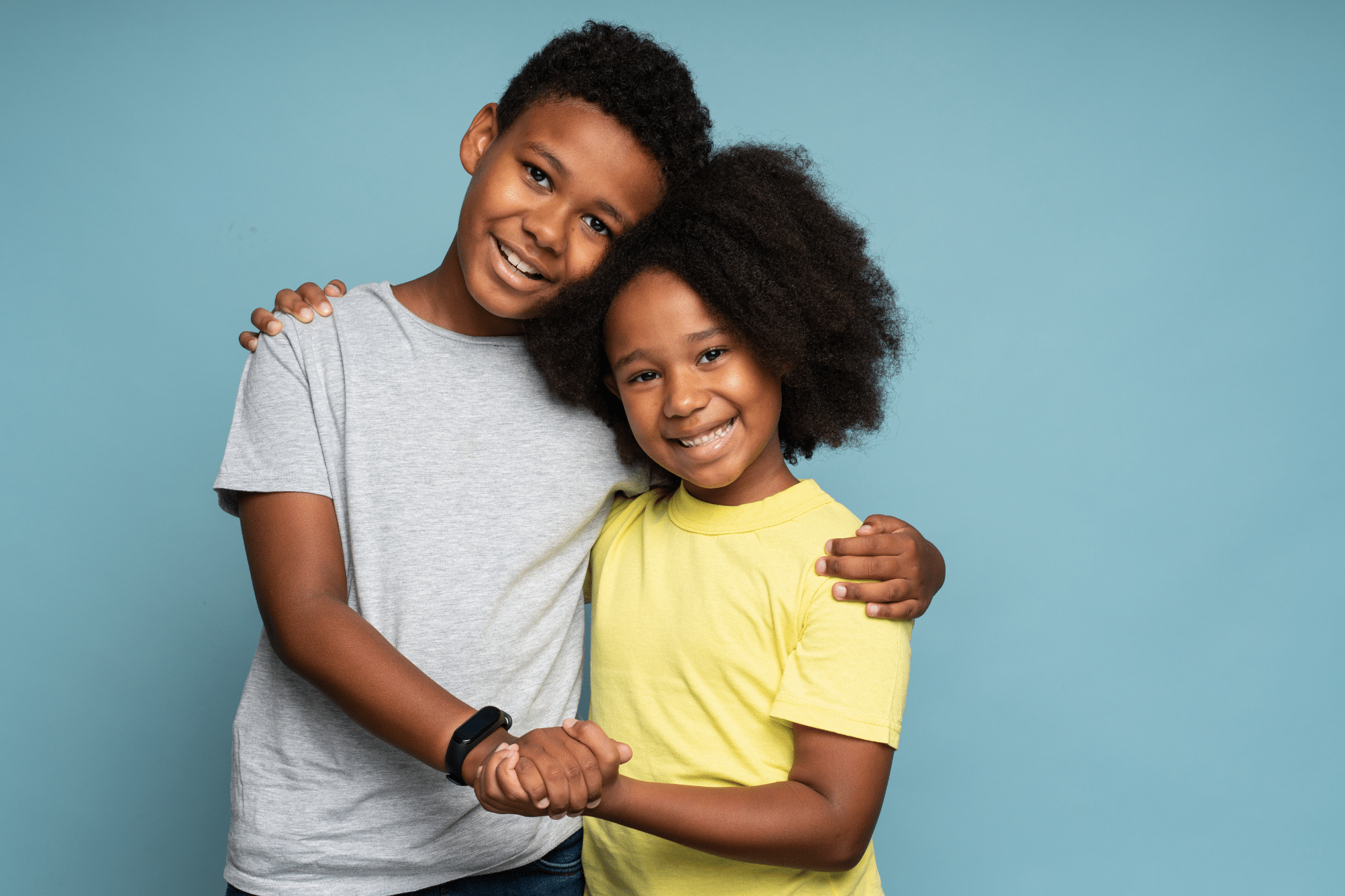 Smiling brother and sister standing together against a blue background