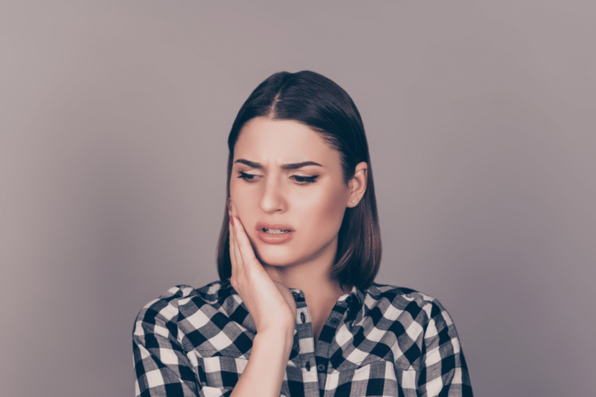 Worried young woman holding her cheek while experiencing tooth pain